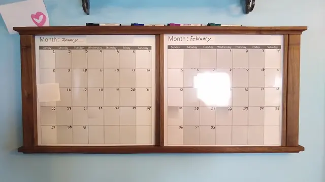 Dry-erase calendars, three month, teo months side-by-side in back, one that slides in front. Trimmed in walnut frame in style of late 1800s window